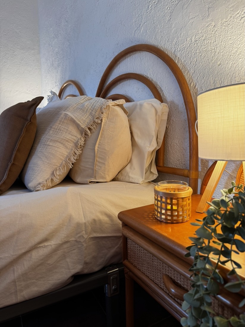 A bedroom with cane headboards and lamplight against a limewashed wall