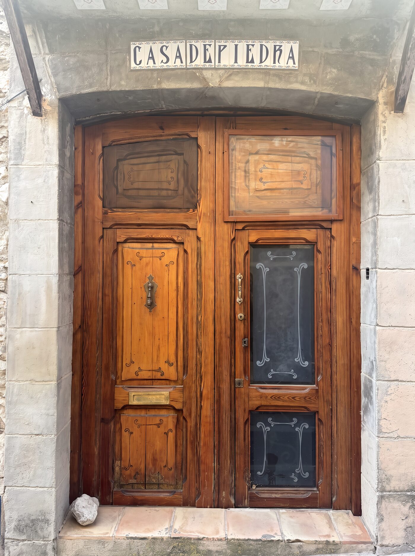 The original carved wooden front door beneath a hand-painted Casa de Piedra tile sign